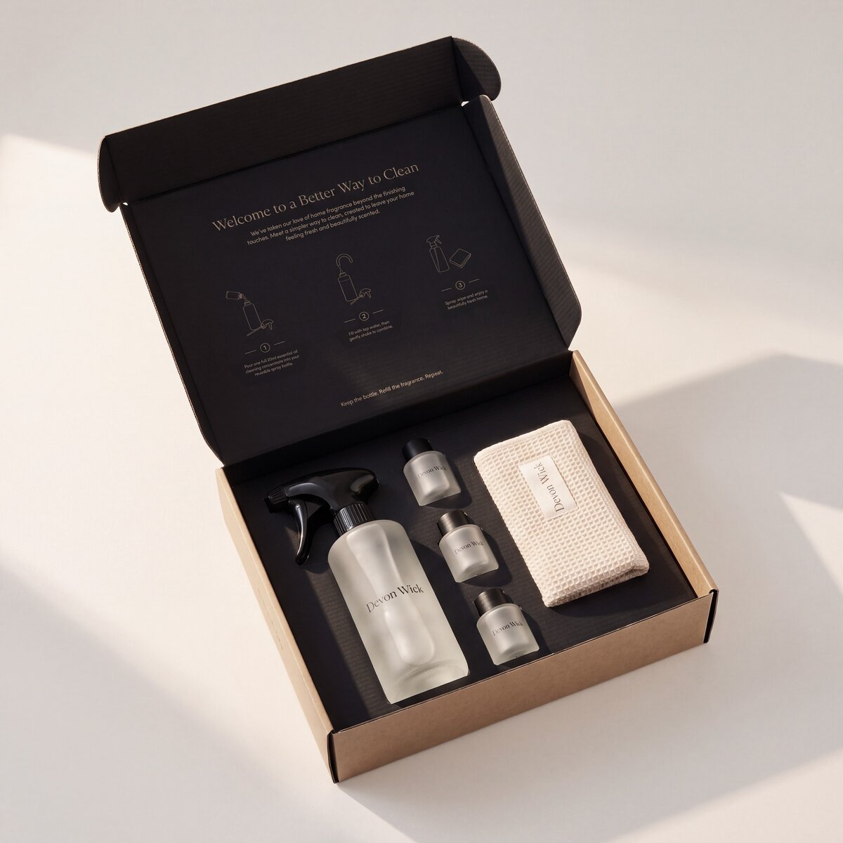 The Signature Cleaning Set gift box, open, with the glass spray bottle, three concentrates and a cloth