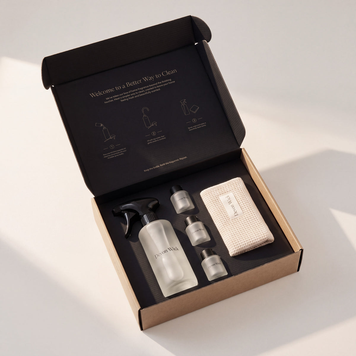 The Signature Cleaning Set gift box, open, with the glass spray bottle, three concentrates and a waffle cloth